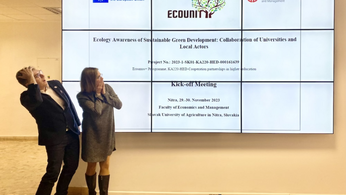 Osoby stojące przed dużym ekranem