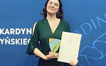 Osoba pozująca do zdjęcia z nagrodą w ręku